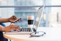 a woman using a laptop and cell phone