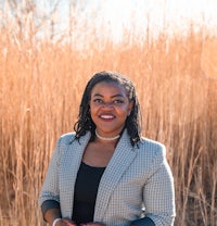 a woman in a blazer standing in tall grass