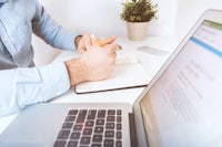 a man sitting at a desk with a laptop and a pen